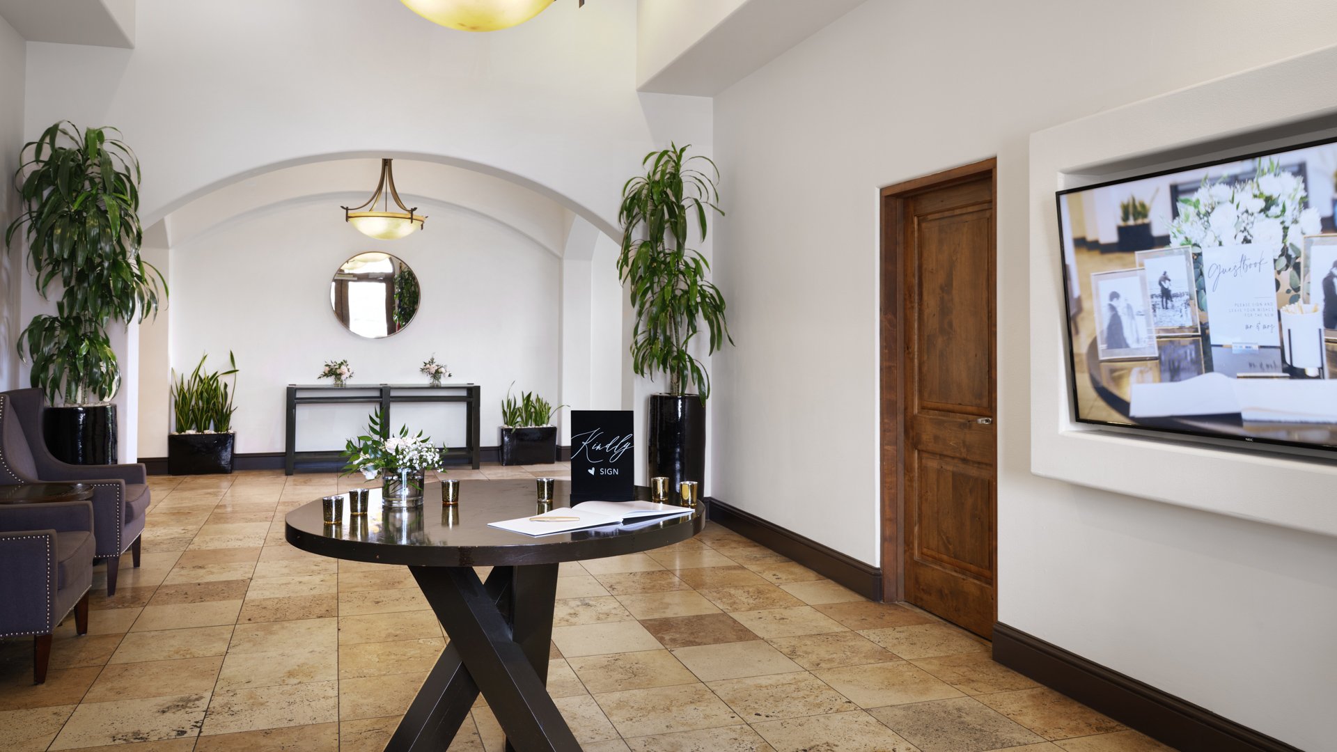 Sophisticated wedding venue entrance lobby with guest book table, pendant lighting, white walls, and wedding planning displays at Aliso Viejo by Wedgewood Weddings California