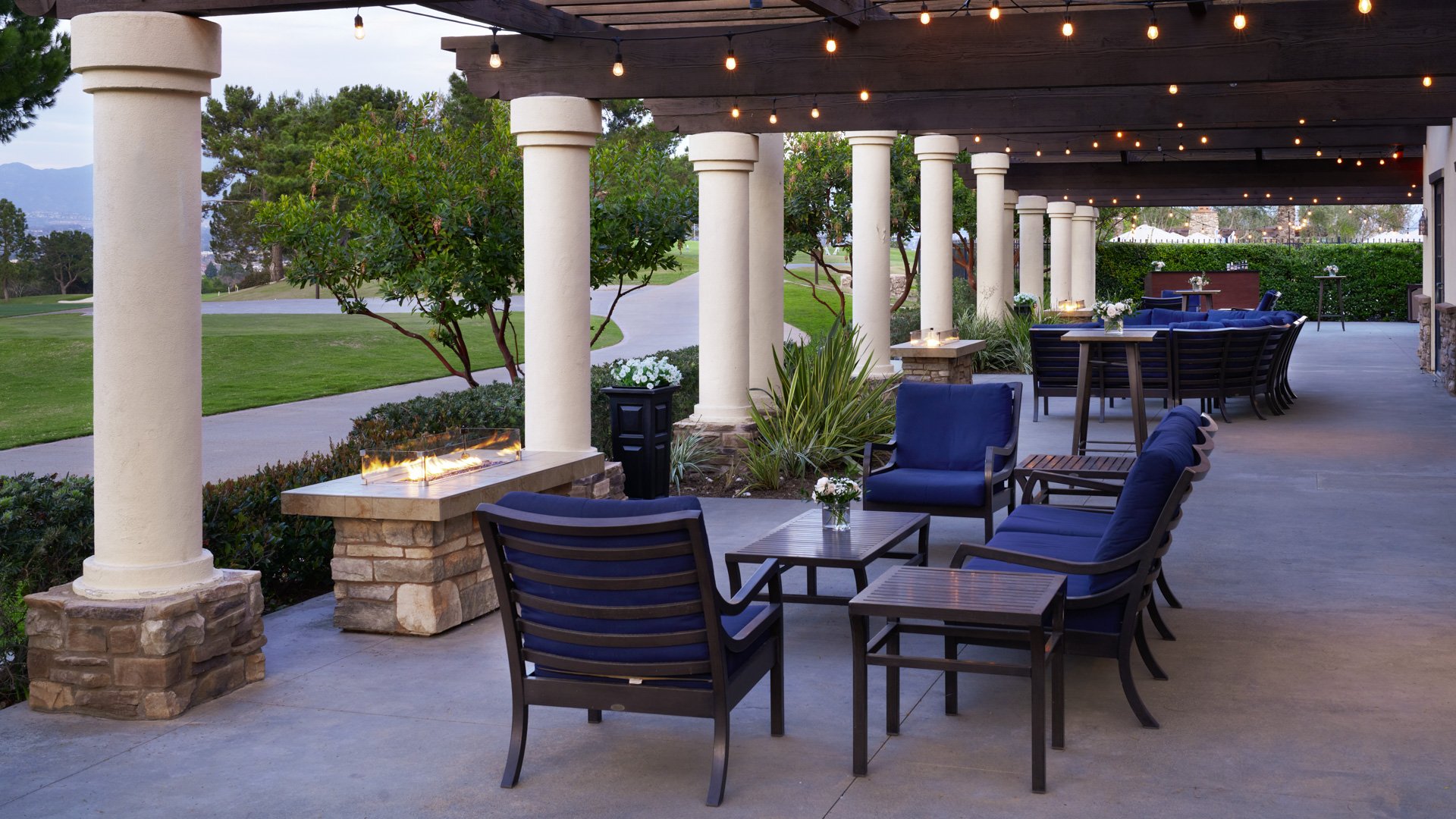 Romantic evening patio reception with string lights, navy cushioned seating, and stone fireplace at Aliso Viejo by Wedgewood Weddings venue