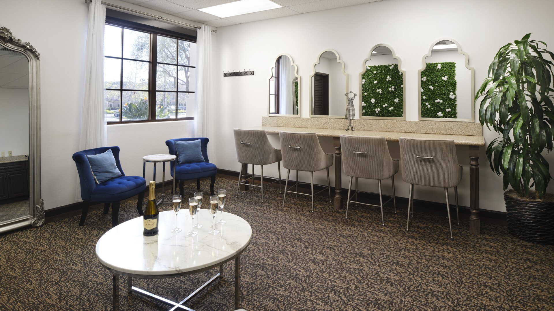 Luxurious suite with vanity stations, arched mirrors, navy velvet chairs, champagne service, and green wall accents at Aliso Viejo by Wedgewood Weddings California
