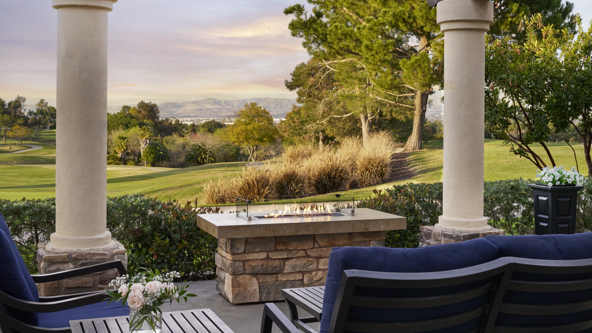 Sophisticated patio lounge area with modern fire table, navy seating, columns, and scenic golf course views at Aliso Viejo by Wedgewood Weddings