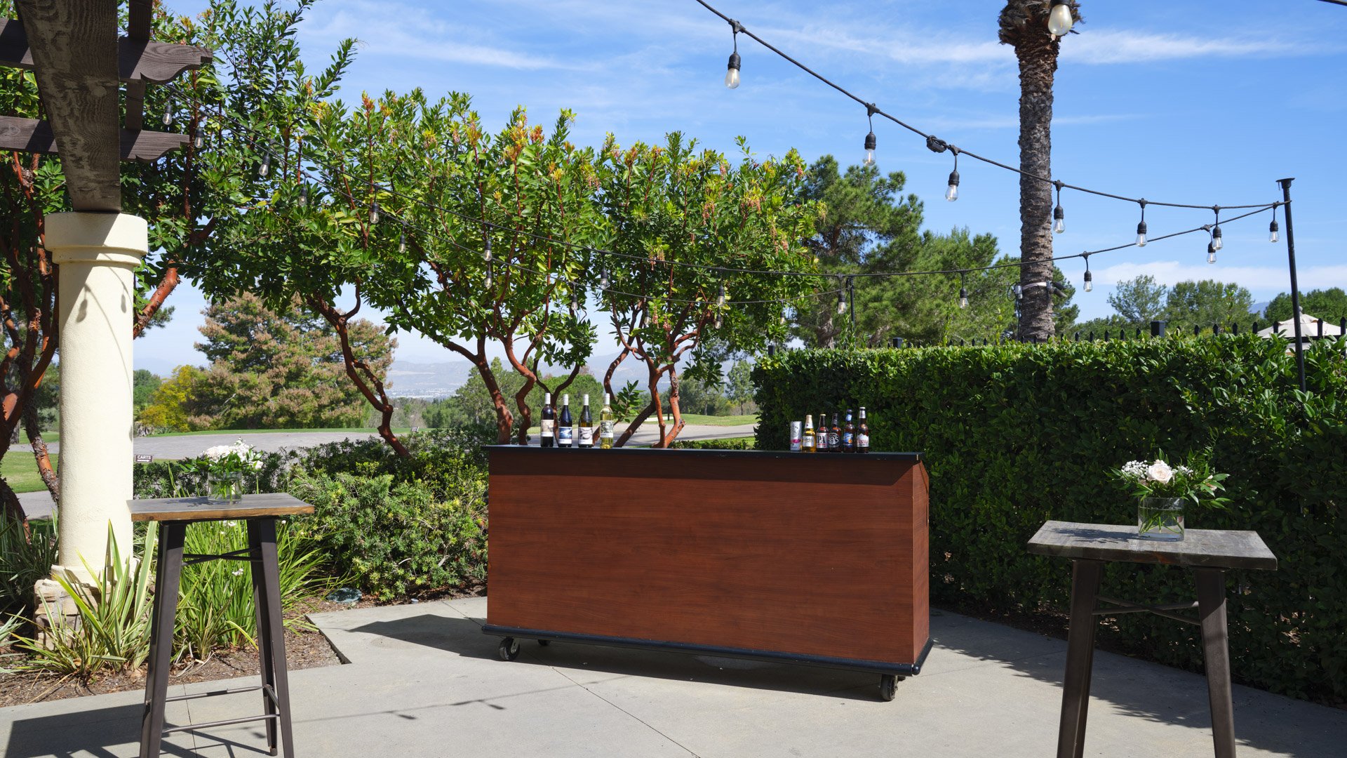 Elegant outdoor bar setup with string lights, wooden bar counter, and golf course backdrop at Aliso Viejo by Wedgewood Weddings California venue