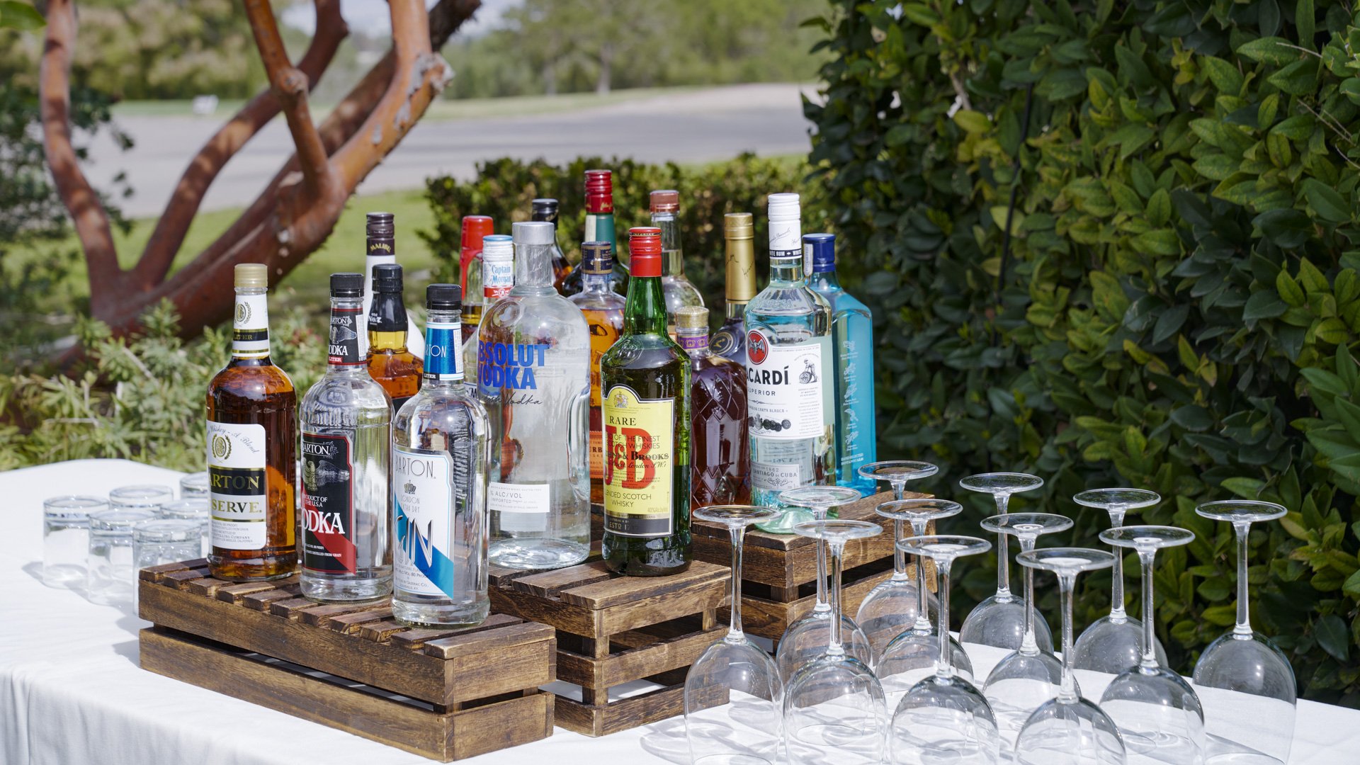 Professional wedding bar display with premium spirits, wine glasses, and wooden serving platforms at Aliso Viejo by Wedgewood Weddings California venue