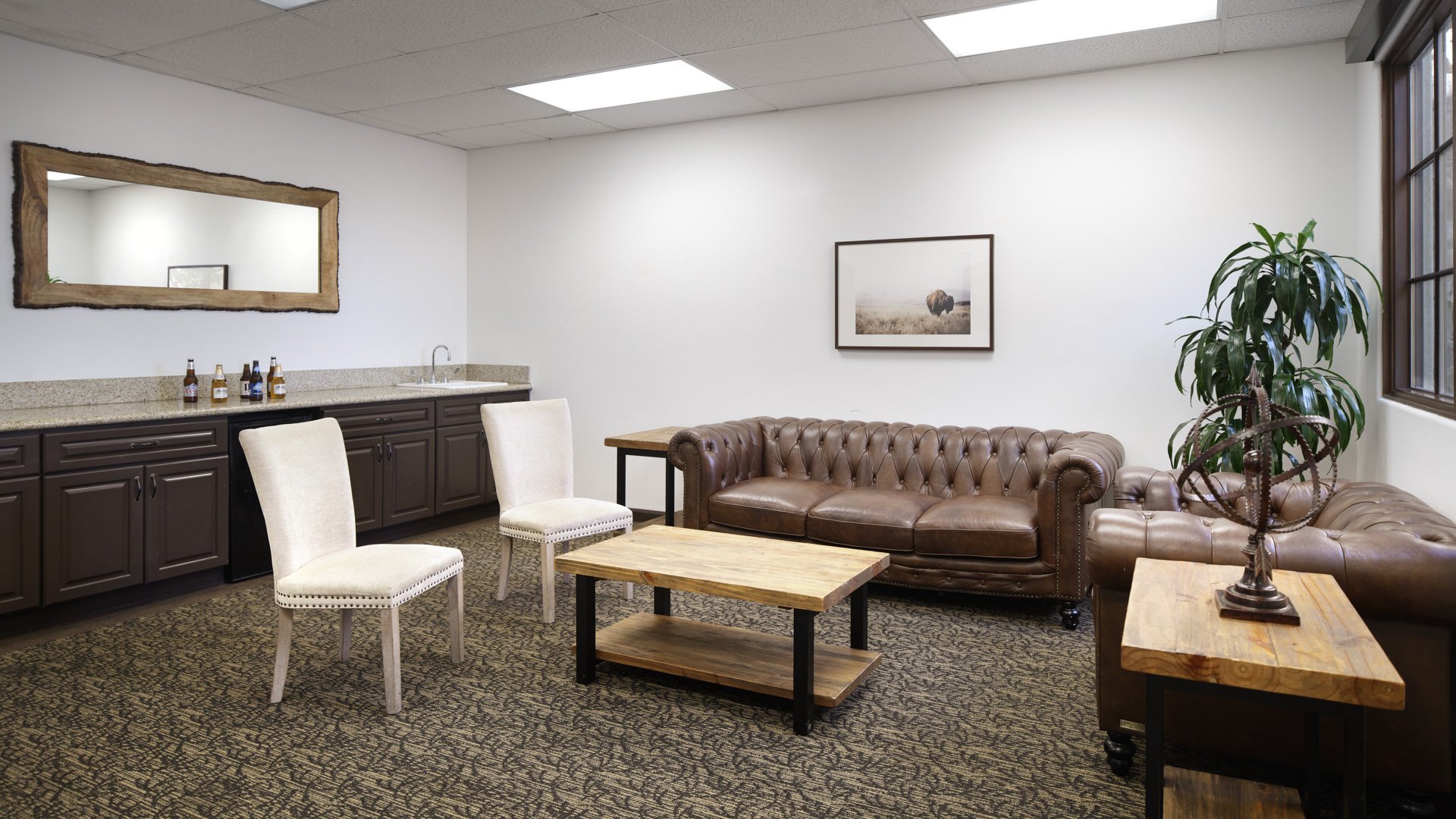 Sophisticated preparation room featuring brown leather Chesterfield sofa, wet bar, wooden furniture, and modern amenities at Aliso Viejo by Wedgewood Weddings venue