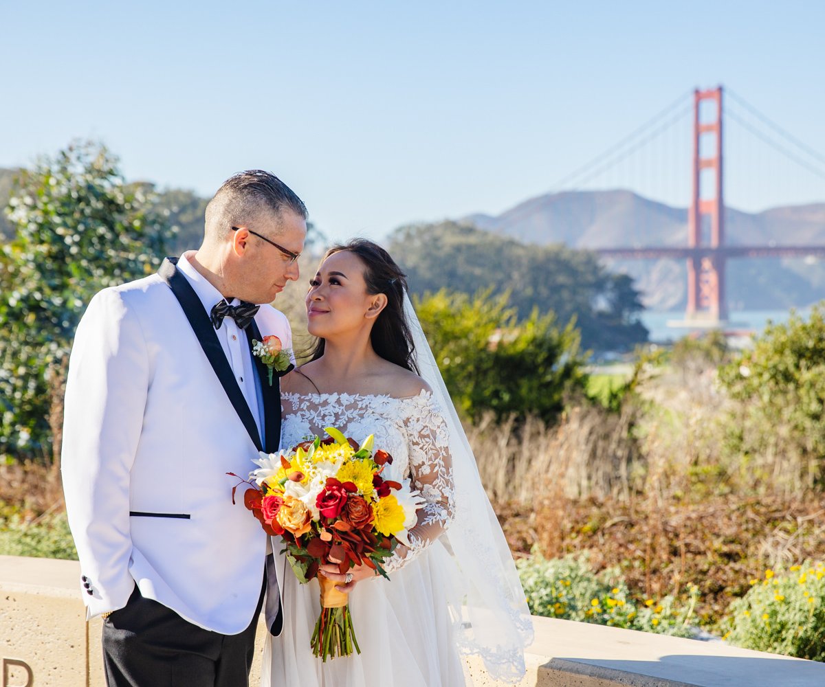 Couple posing in front of the Golden Gate Bridge after their wedding - Golden Gate Club at the Presidio - Wedgewood Weddings - 1