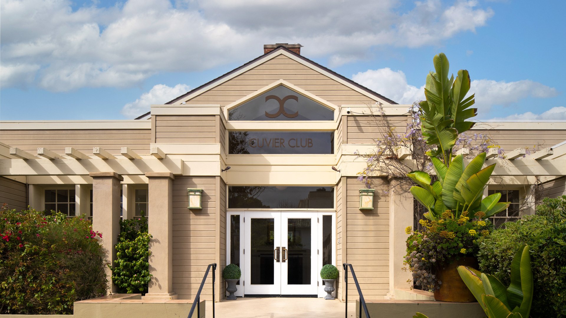 Classic exterior entrance of Cuvier Club by Wedgewood Weddings in La Jolla featuring elegant white doors, tropical landscaping, and traditional California architecture perfect for weddings
