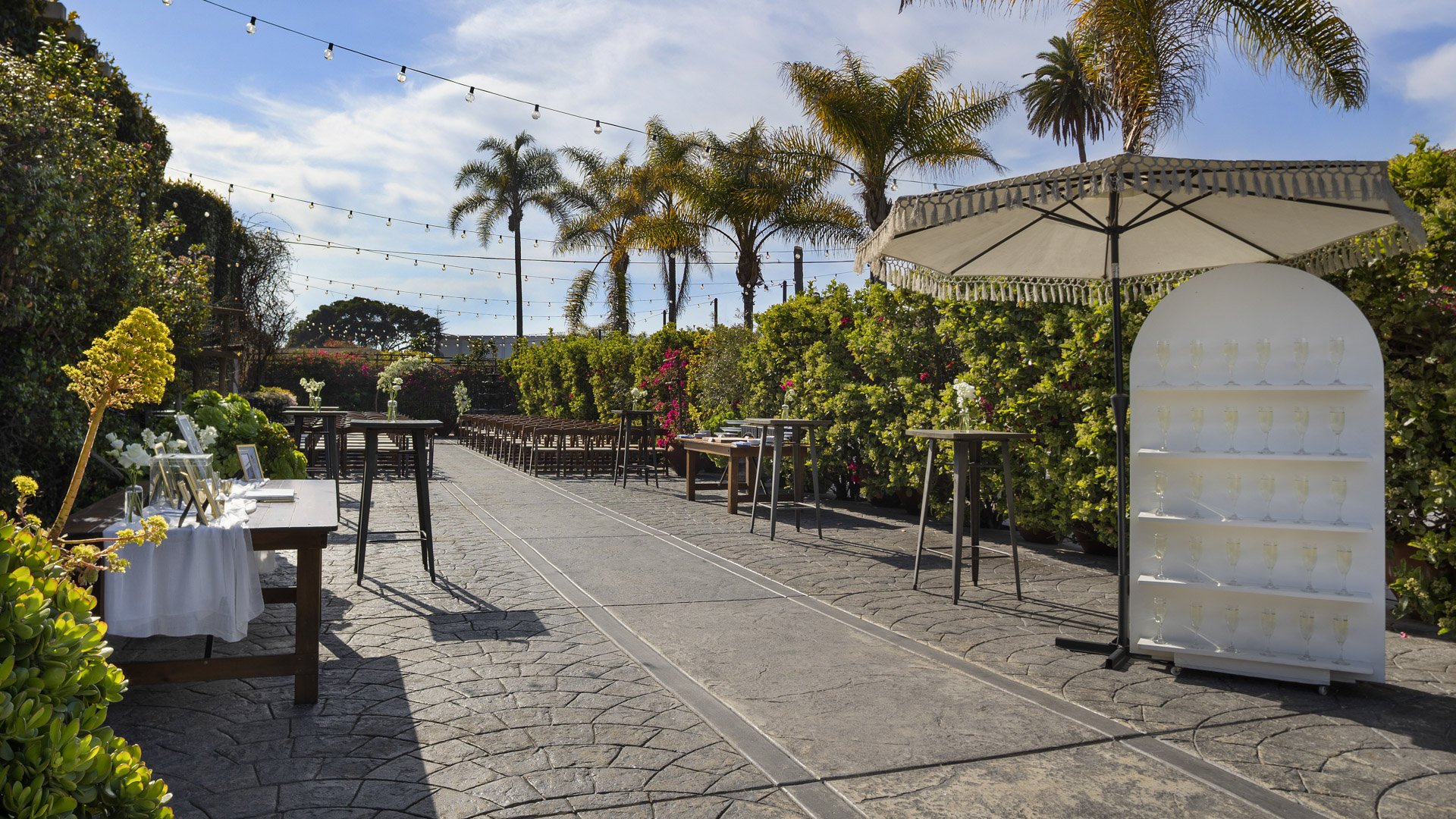 Garden Courtyard cocktail hour area at Cuvier Club featuring high-top tables, tropical landscaping, ocean views, and string lighting perfect for La Jolla weddings