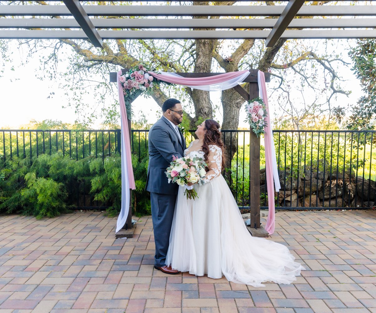 Bride and groom posing outdoors in front of ceremony arch with pink and white florals - Evergreen Springs by Wedgewood Weddings - 14