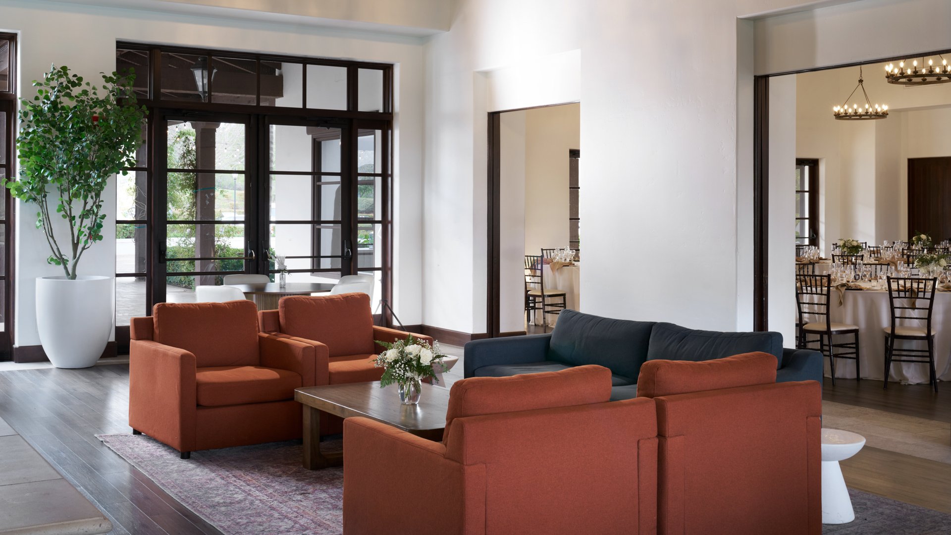 Comfortable wedding reception lounge at Fallbrook Estate featuring modern furniture, floor-to-ceiling windows, open layout connecting to dining area and contemporary Spanish colonial design