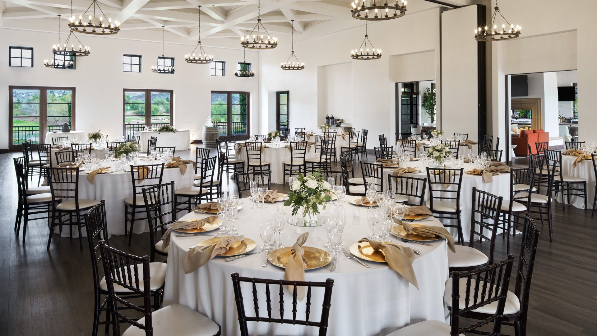 Spacious wedding reception ballroom at Fallbrook Estate Wedgewood Weddings with coffered ceiling, wrought iron chandeliers, round tables and garden views through French doors