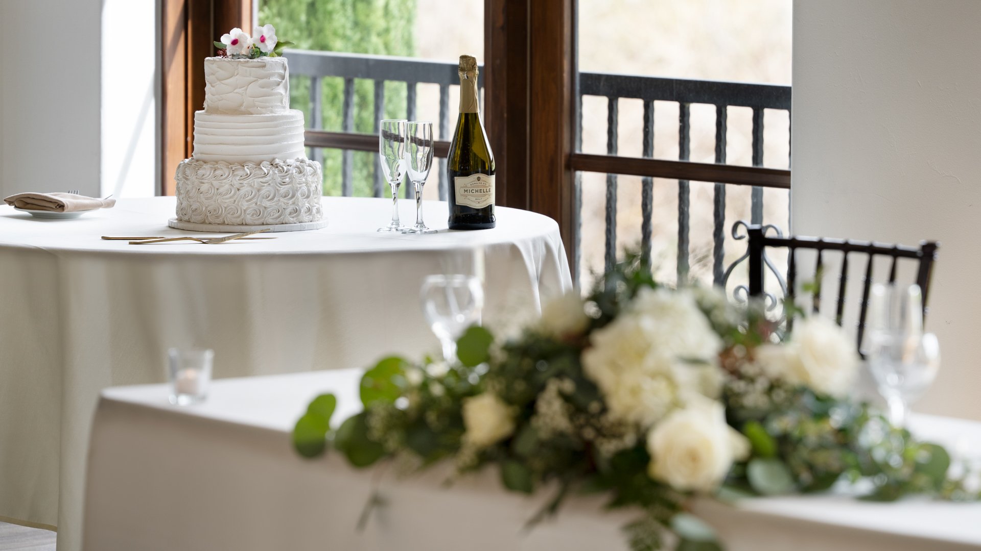 Elegant three-tier wedding cake with white roses and champagne toast setup at Fallbrook Estate by Wedgewood Weddings featuring tiered cake design, crystal flutes and romantic floral arrangements