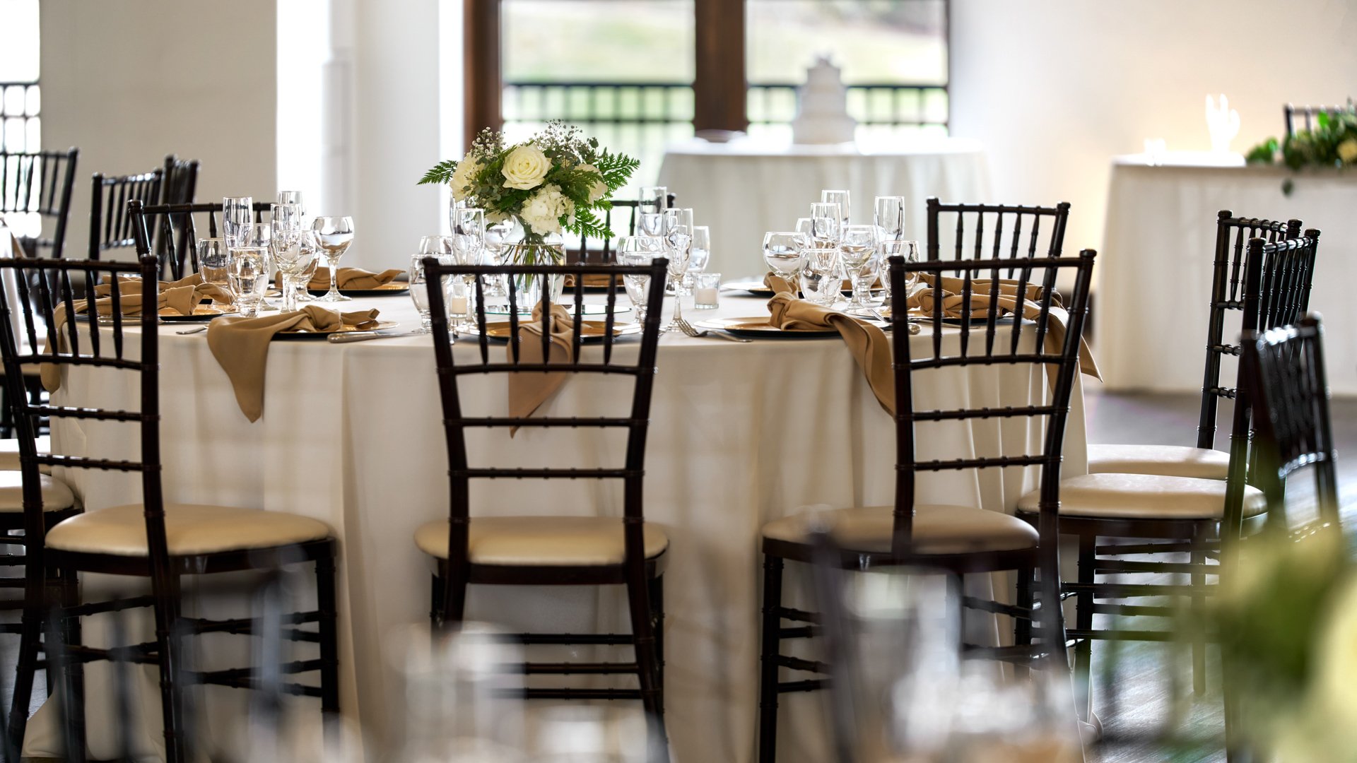 Sophisticated wedding reception table setting at Fallbrook Estate Wedgewood Weddings with white roses centerpiece, gold napkins, crystal stemware and Chiavari chairs with garden views