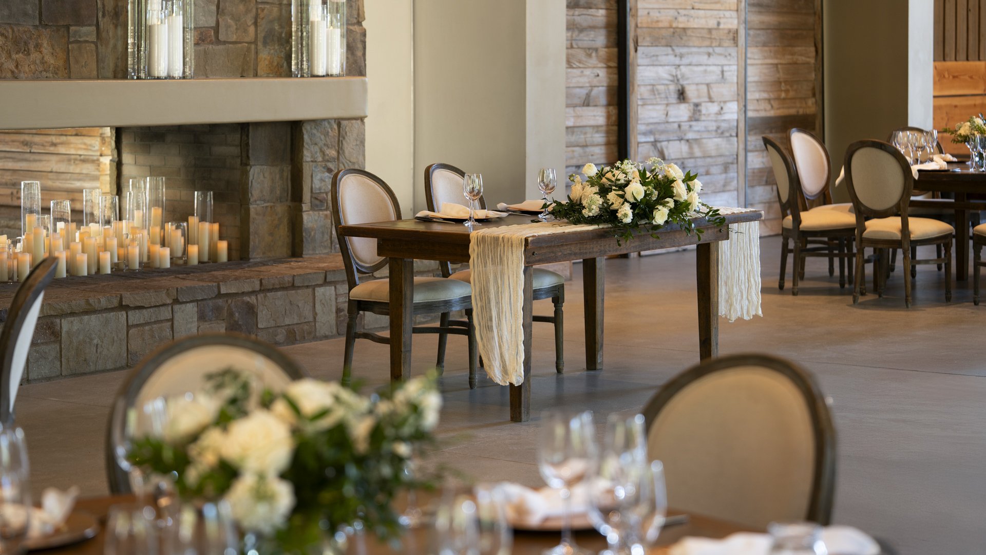 Romantic fireplace dining area at Galway Downs featuring stone fireplace, candlelit ambiance, elegant table settings with white florals, and intimate seating for special wedding moments in Temecula