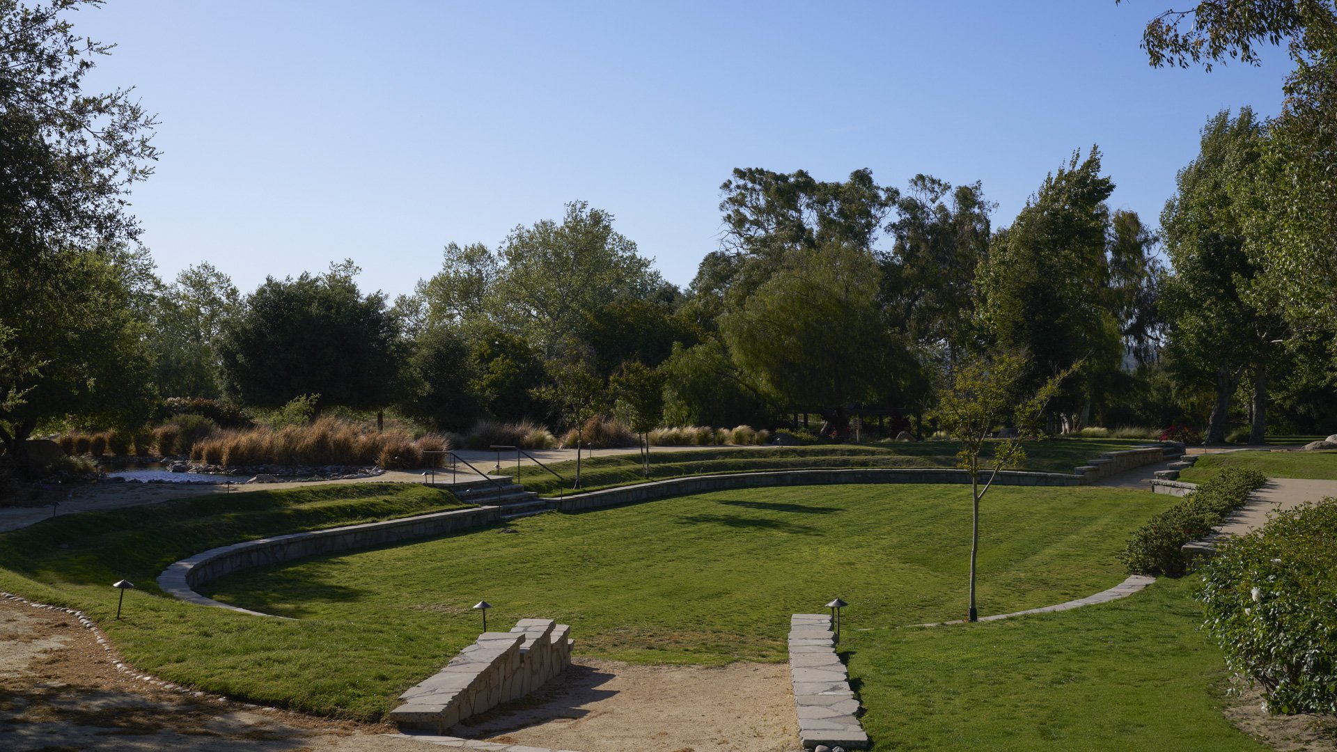 Expansive multi-level amphitheater grounds at Galway Downs featuring tiered grass areas, stone retaining walls, mature trees, and open lawn spaces perfect for large outdoor weddings in Temecula wine country