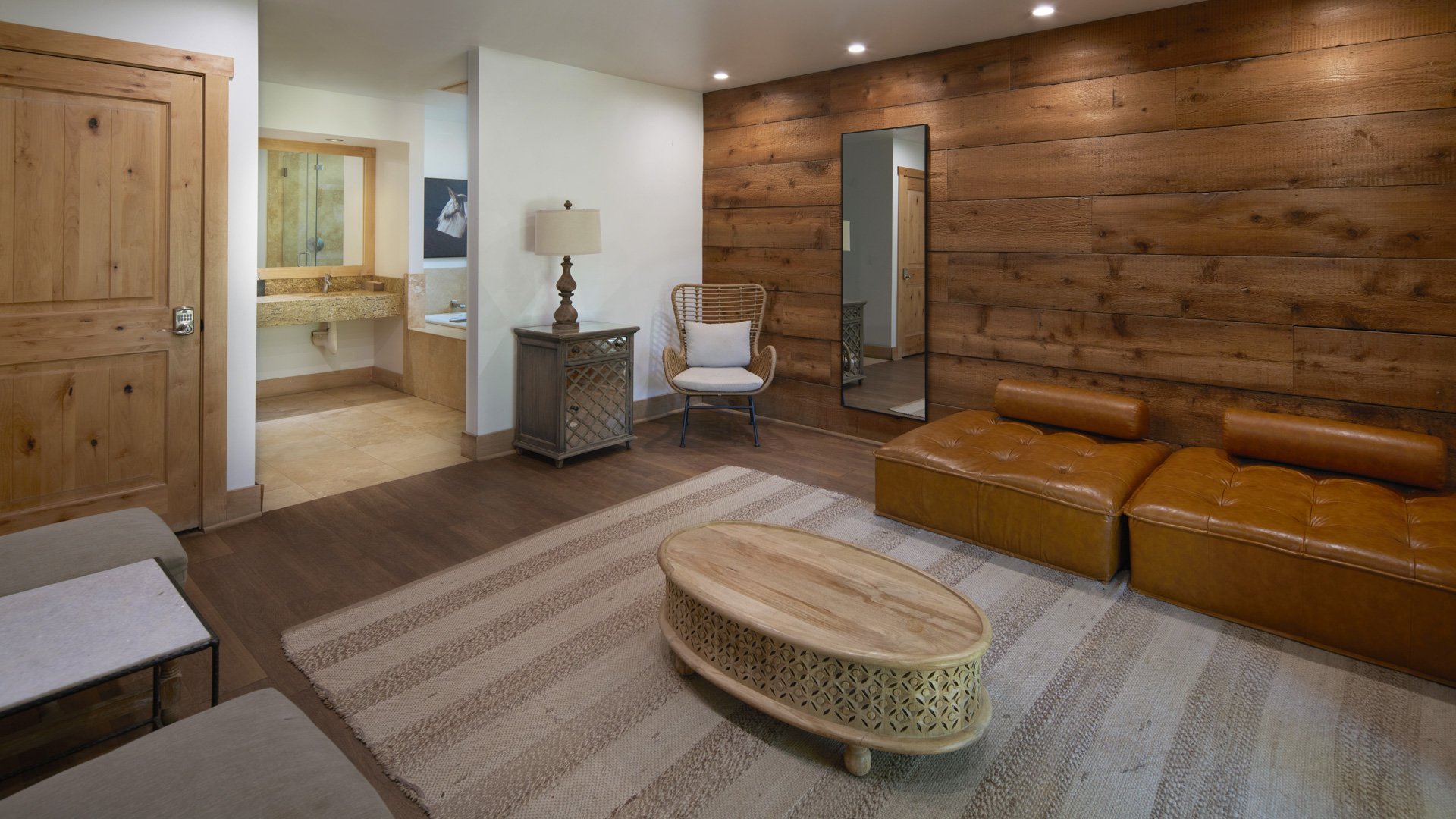 Spacious bridal preparation room in Galway Downs Wedding Suites with reclaimed wood accent wall, leather seating, modern amenities, and private bathroom for getting ready in Temecula