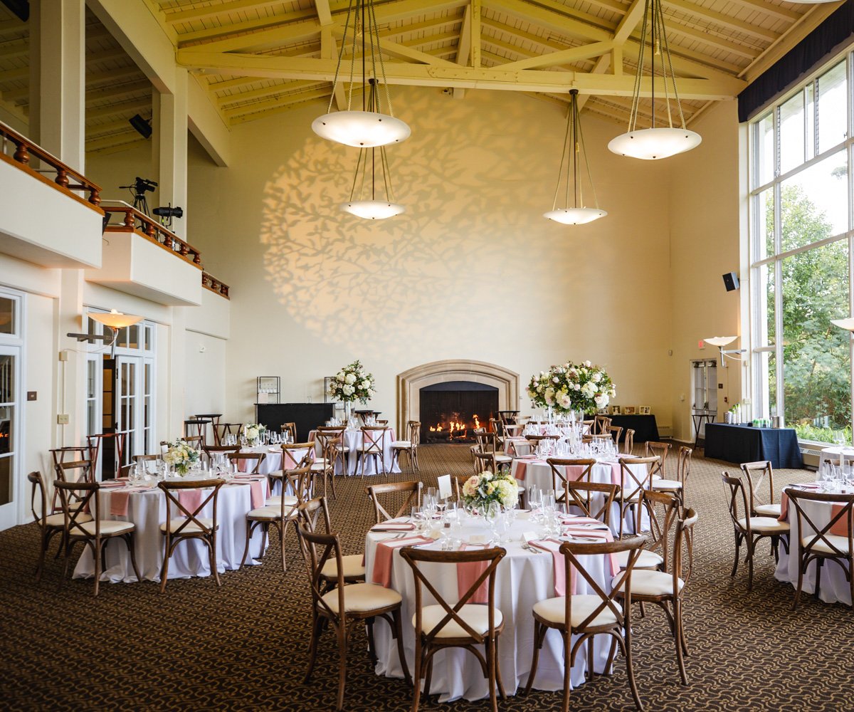 Ballroom wedding reception with accent lighting, cross back chairs, and white florals - Golden Gate Club at the Presidio - Wedgewood Weddings - 1