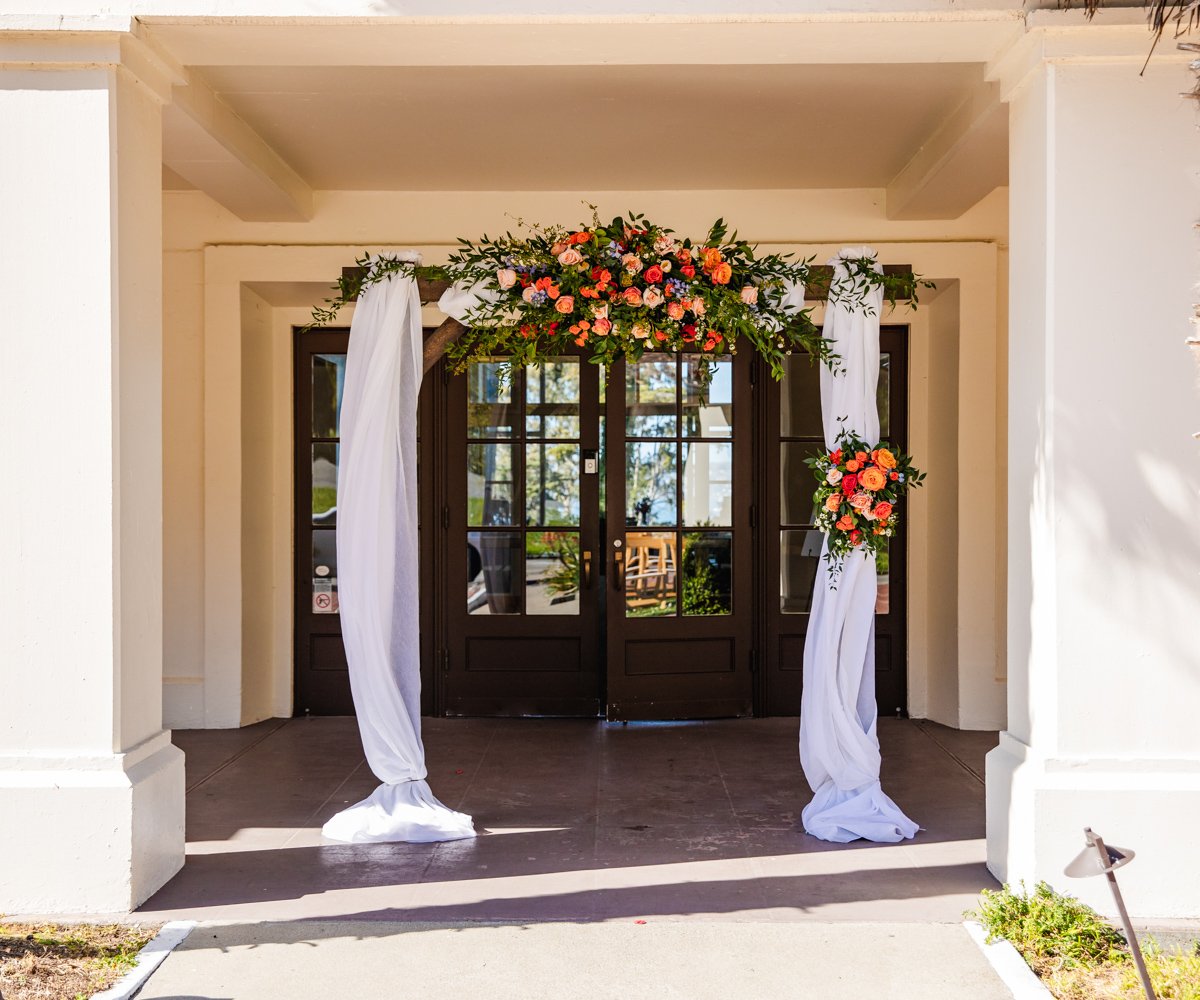 Outdoor wedding ceremony arch in front of building with vibrant florals - Golden Gate Club at the Presidio - Wedgewood Weddings - 2