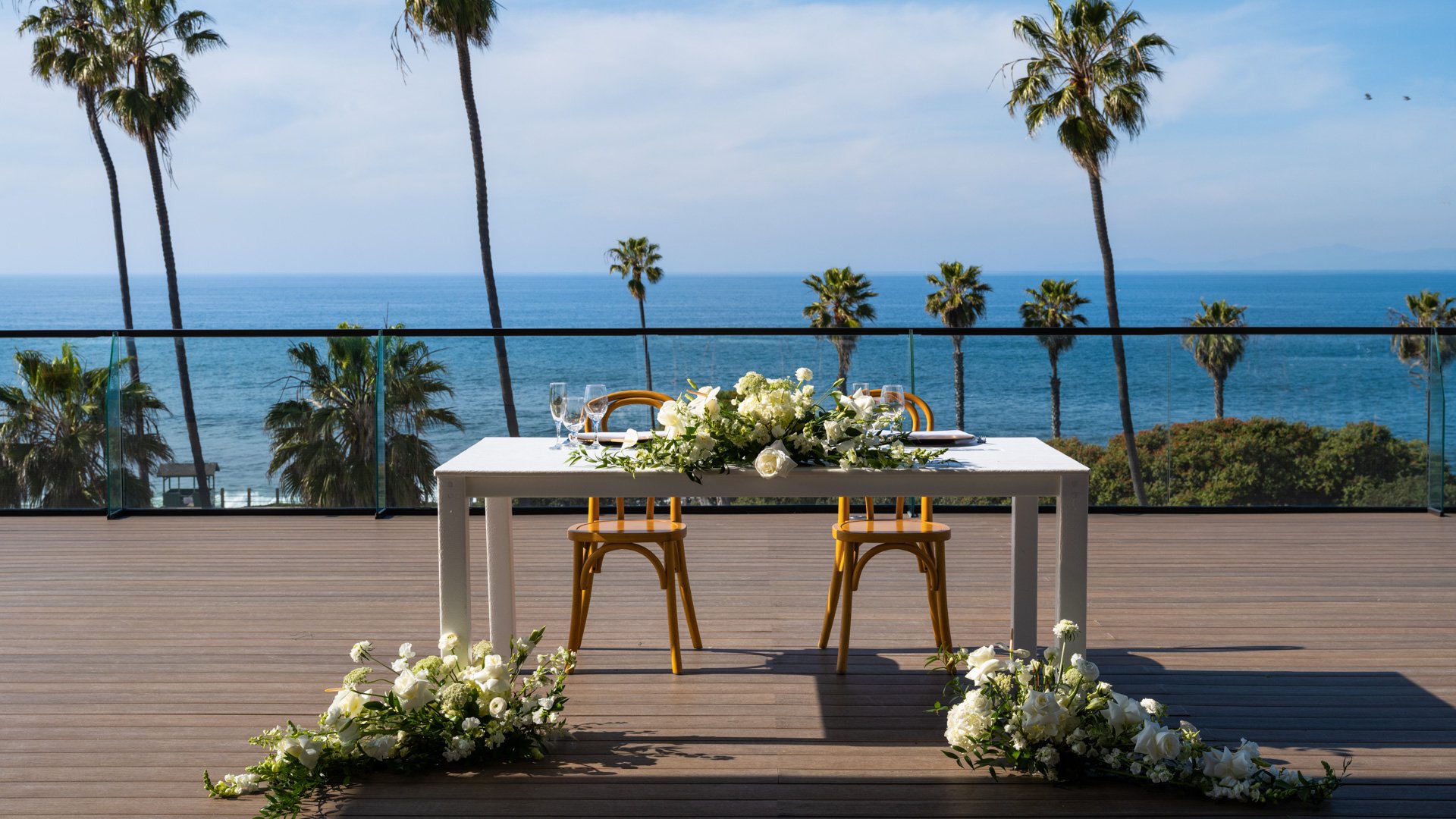 Romantic sweetheart table for two with white florals, bentwood chairs, and panoramic Pacific Ocean backdrop at La Jolla Cove Rooftop wedding venue