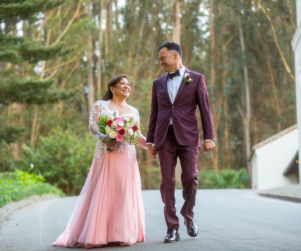 Bride and groom stroll hand in hand after wedding ceremony - bride is wearing pink wedding dress - Presidio Chapel at the Golden Gate Club - Wedgewood Weddings