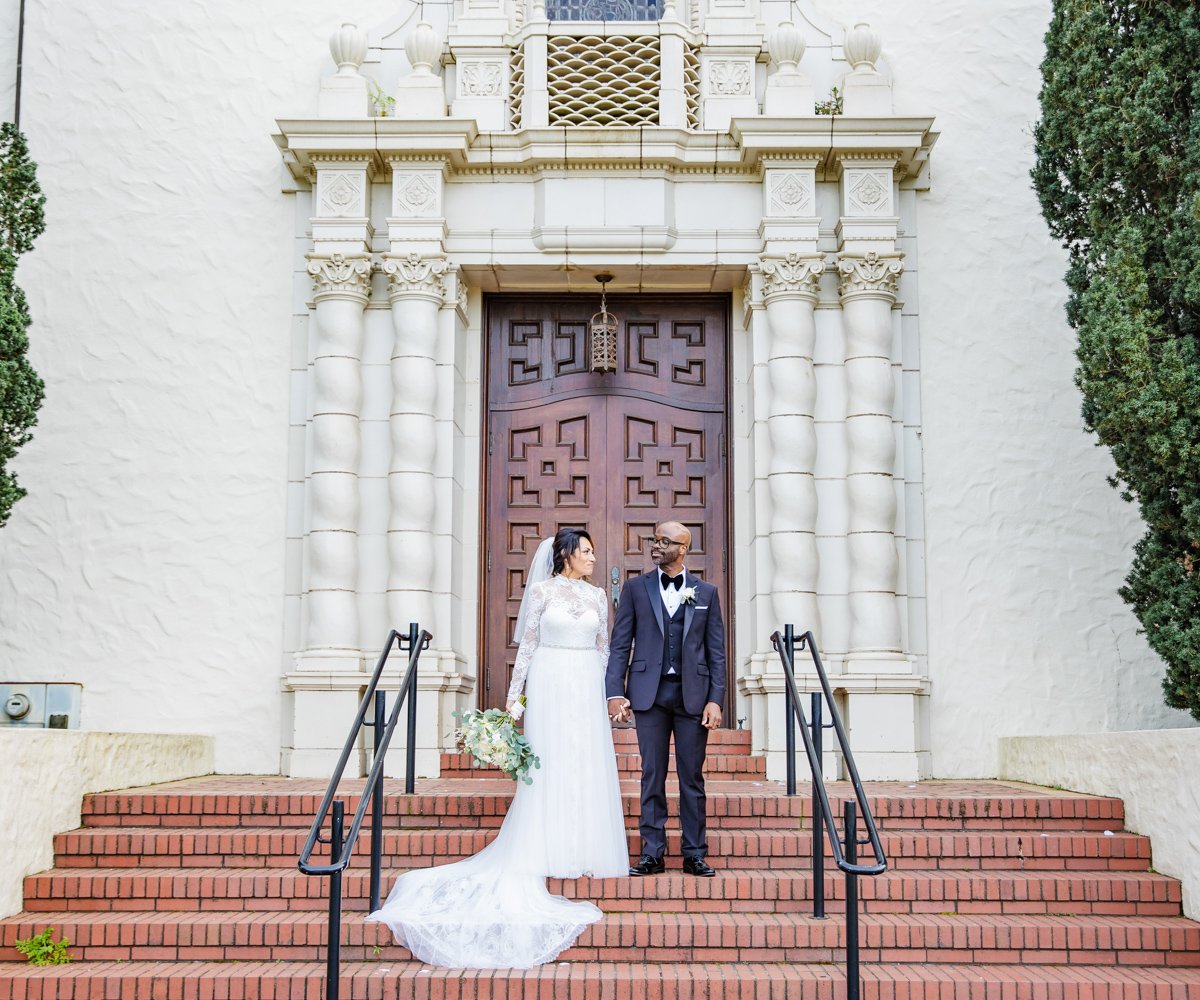 Newlyweds smile at each other in front of historic church - Presidio Chapel at the Golden Gate Club - Wedgewood Weddings