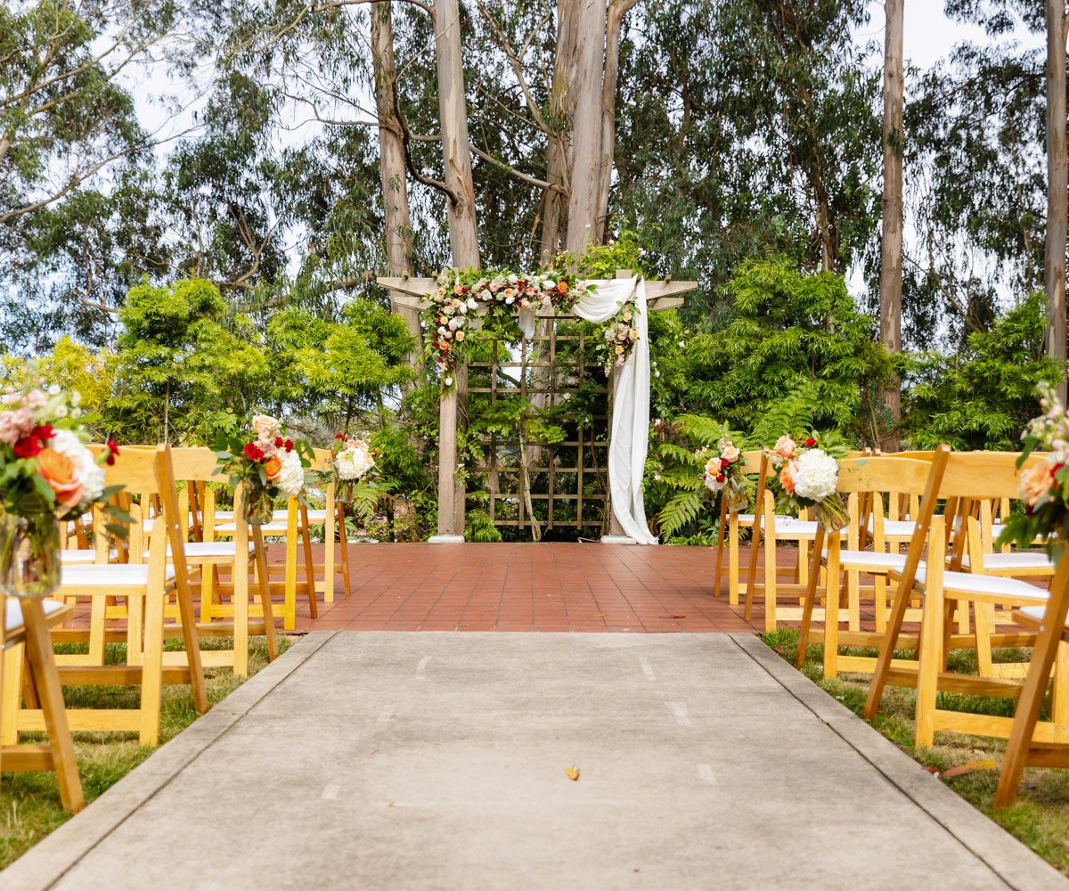 Outdoor ceremony site with vibrant florals in the historic Presidio Park - Presidio Chapel at the Golden Gate Club - Wedgewood Weddings