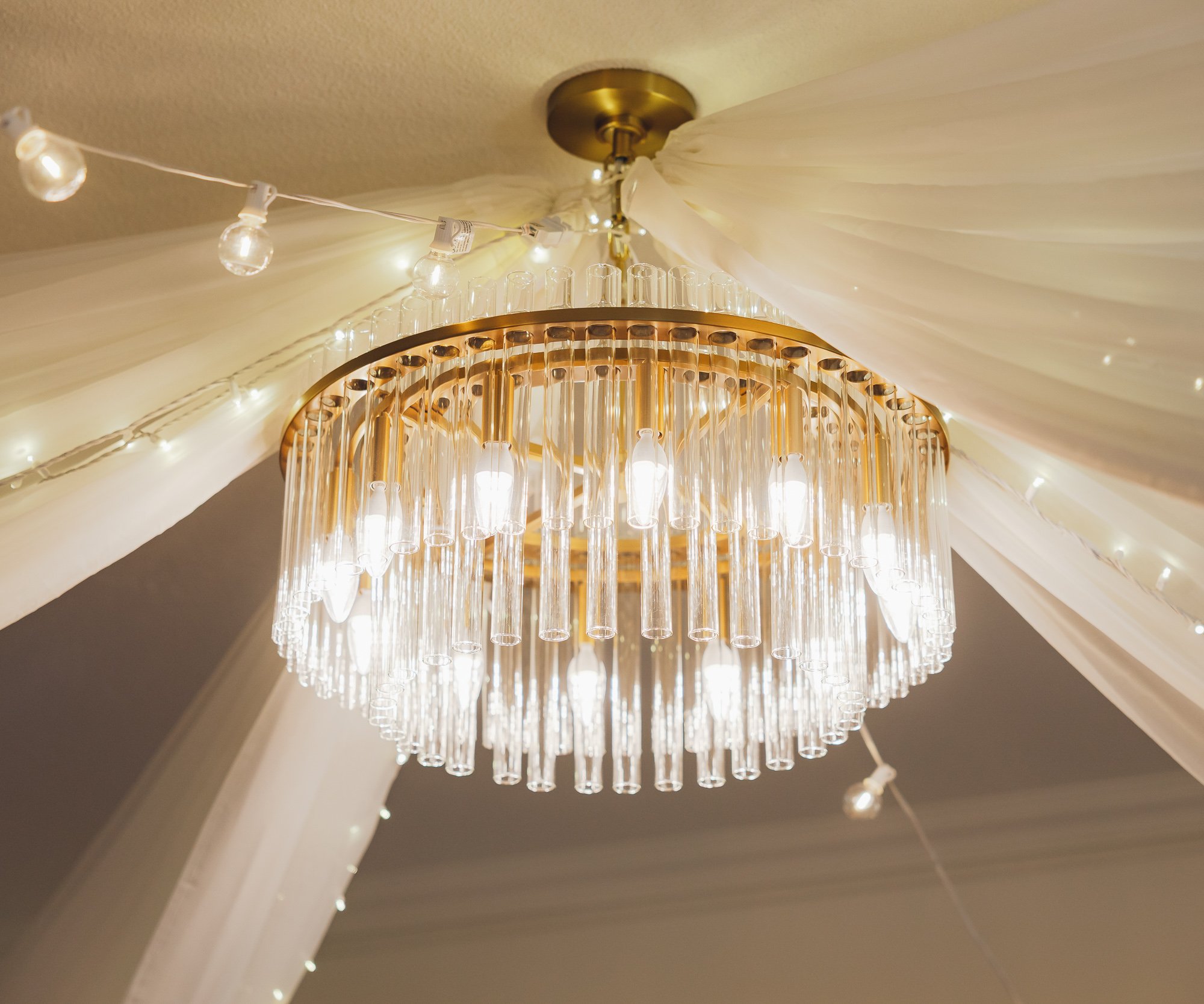 Close-up of elegant tiered crystal chandelier with white ceiling and architectural details