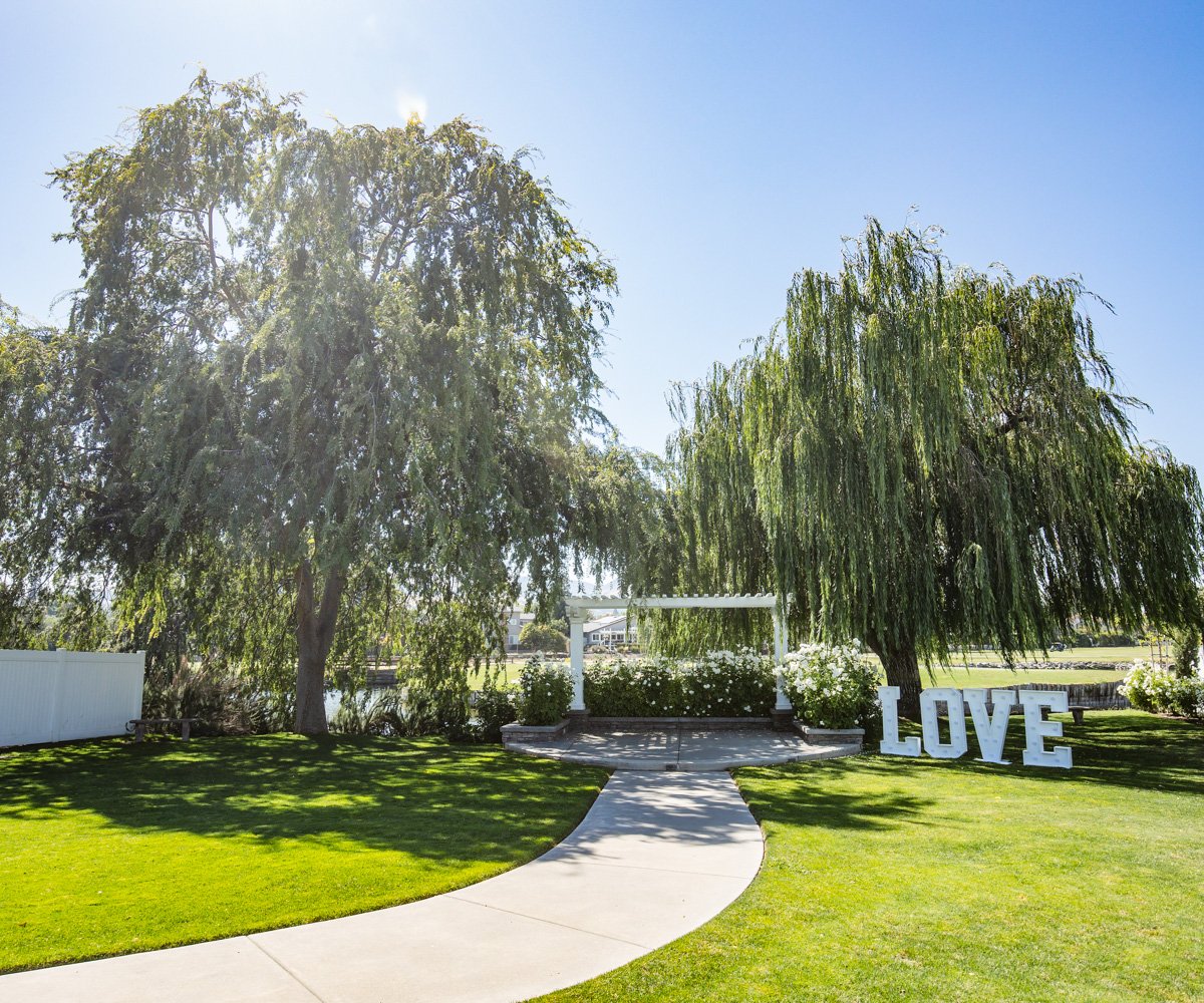 Outdoor ceremony site surrounded by weeping willows and lush greenery - San Ramon Waters by Wedgewood Weddings