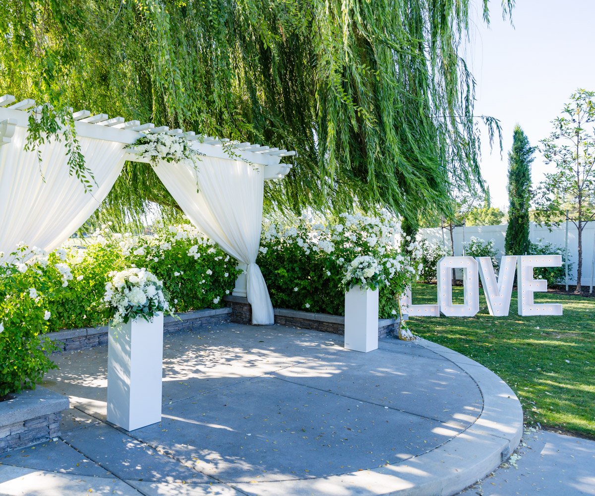 Outdoor ceremony with Love yard decoration and white flowers - San Ramon Waters by Wedgewood Weddings