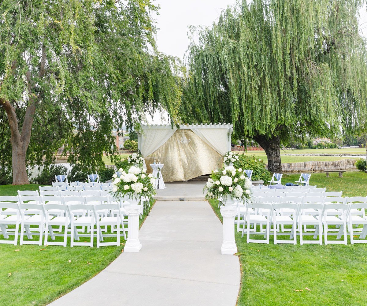 Wedding ceremony site with gold drapery and white florals - San Ramon Waters by Wedgewood Weddings