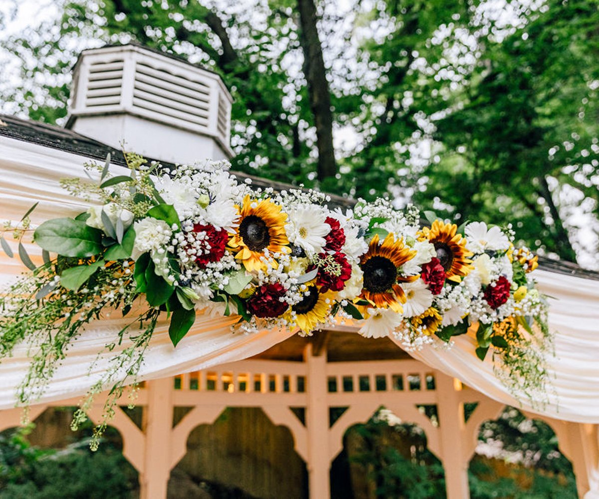 Sunflowers, daisies, and red carnations on ceremony gazebo - Tapestry House by Wedgewood Weddings