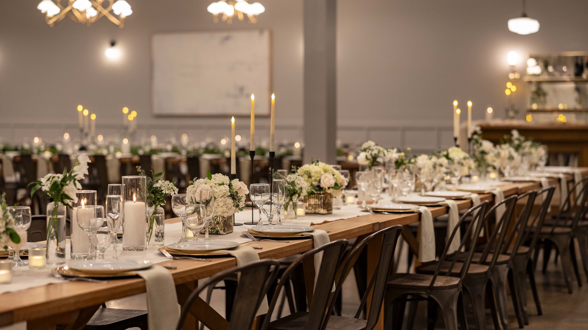 Beautiful table settings with taper candles, white floral arrangements, and gold accents
