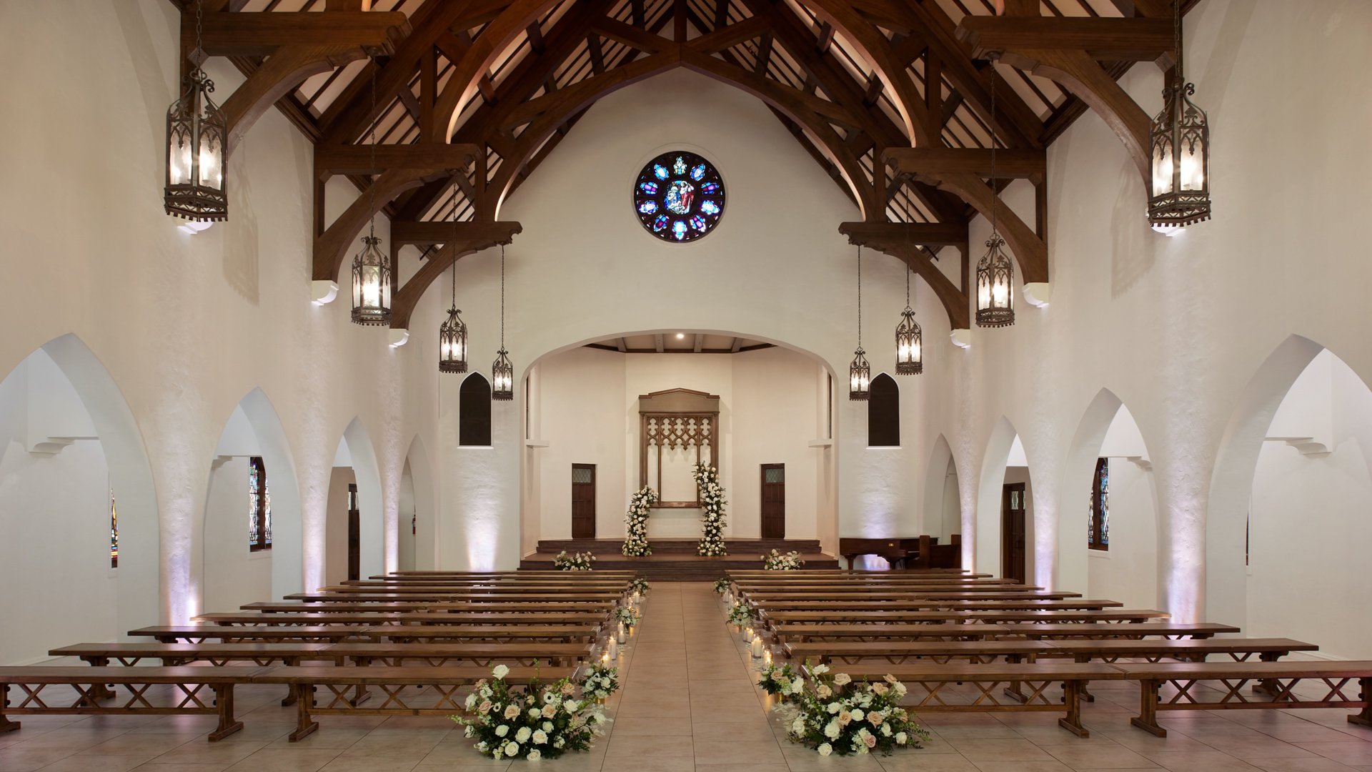 Elegant wedding ceremony setup in The Sanctuary Cathedral, Long Beach, with rose window and floral aisle arrangements.
